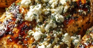 Plate of Greek Chicken with Lemon and Feta, garnished with herbs.