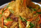 A plate of colorful Singapore Noodles with vegetables and shrimp