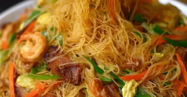 A plate of colorful Singapore Noodles with vegetables and shrimp