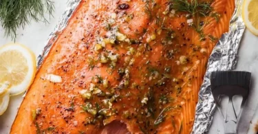 Delicious smoked salmon displayed on a wooden platter with fresh herbs.